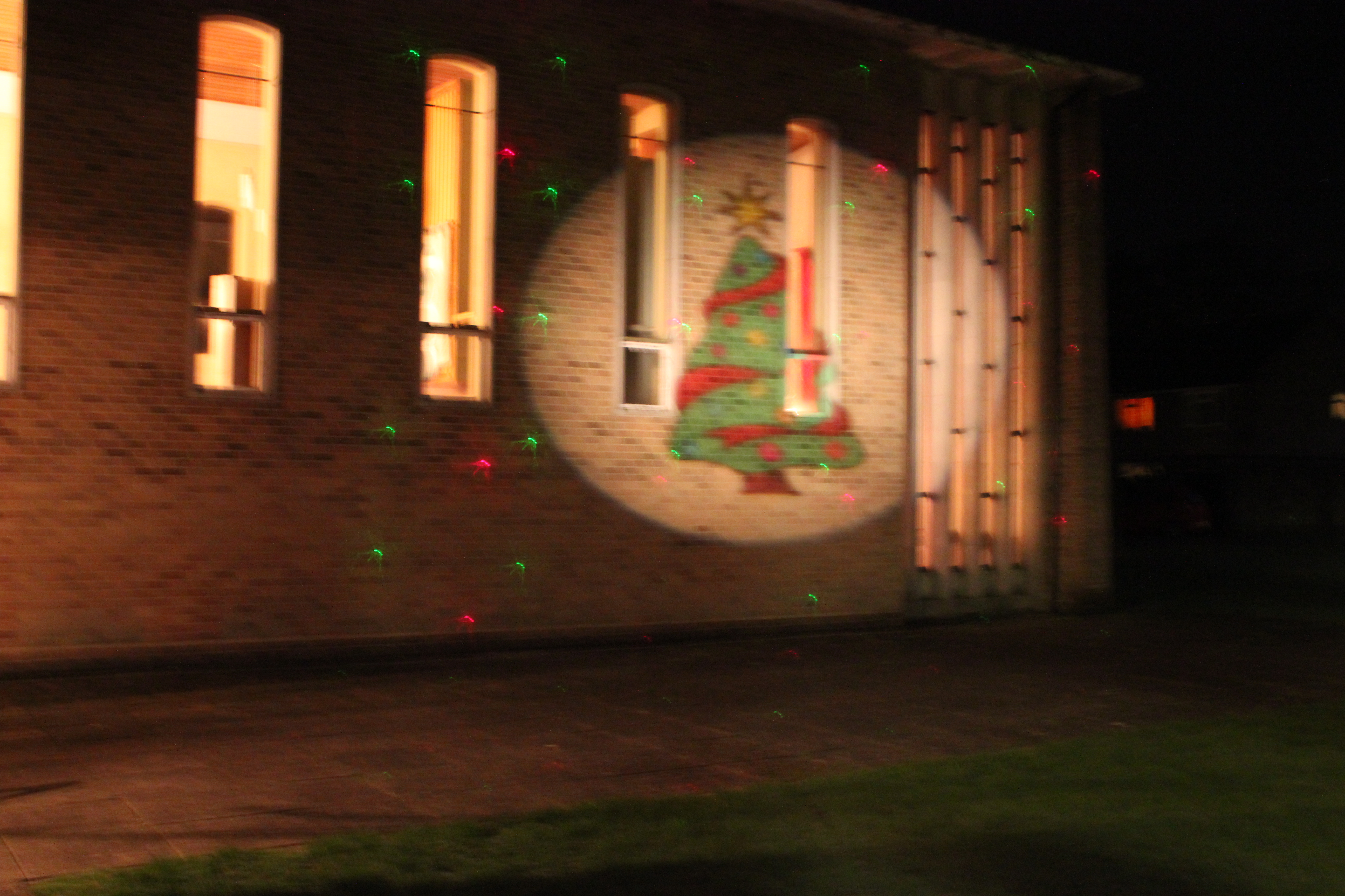 Picture shows the outside of the church with a light projection of a Christmas tree with coloured laser stars.